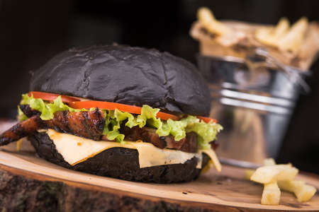 tasty black burger with french fries, snack in the restaurantの写真素材