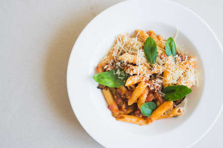 penne pasta with tomato and basil sauce on white plateの写真素材