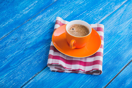 orange cup of coffee with napkin on blue retro tableの写真素材