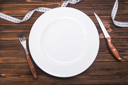 weight loss concept. plate with fork, knife and spoon on backgroundの写真素材