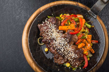 Grilled meat with sesame and grilled vegetables in a frying pan. restaurant serving mealsの写真素材
