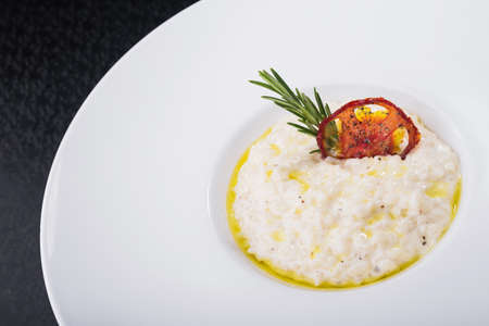 classic rice risotto with rosemary branch in white plateの写真素材