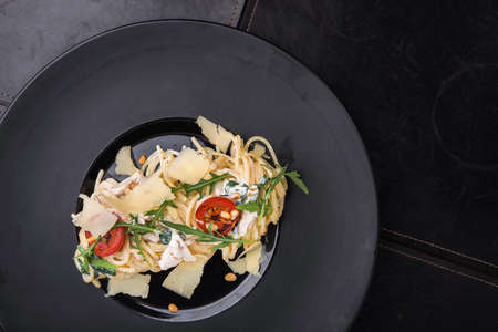 tasty pasta spaghetti with tomato in black dishの写真素材