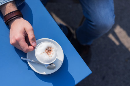 man holding a mug of coffee in a restaurant, a table on the streetの写真素材