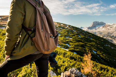 a mountain hiker with a backpack and a camera on top of a mountain alps in the hillsの写真素材