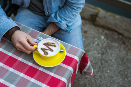 Man with a yellow cup of coffee, morning by the river on the pier with hot drinkの写真素材