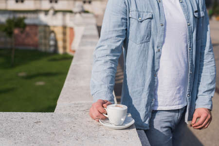 young guy with coffee mug on the street, coffee break in a parkの写真素材