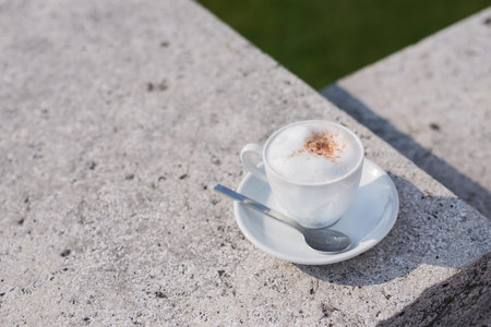 White coffee cup with foam on a street at green park, sunny dayの写真素材