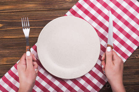 woman hand with knife and fork. top view of plate, wooden tableの写真素材