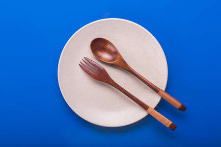 Empty white plate with wood spoon and fork. top viewの写真素材