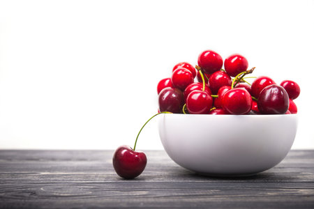 fresh red cherry fruit in plate on wood table isolated on white background