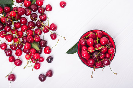 fresh red cherry fruit in plate on wood table. top view