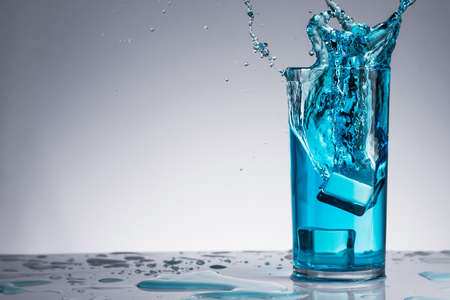 Glass of water with splash and drops on a backgroundの写真素材