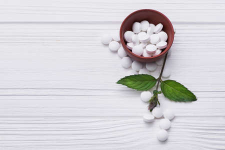 Natural organic pills with herbal plant on white wood table. ethnoscience conceptの写真素材