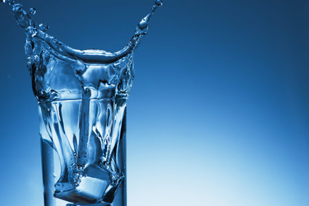 Glass of water with splash and drops on a background