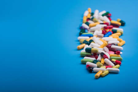 Colored pills and medical capsule on blue backgroundの写真素材