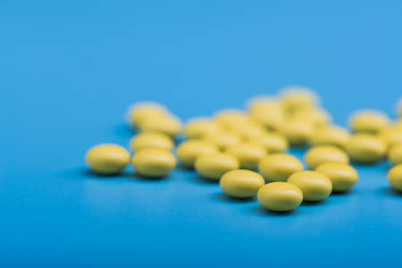 Yellow medical pills on a blue background. medicine conceptの写真素材