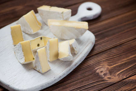 pieces of cheese brie set on white wooden board. milk product backgroundの写真素材