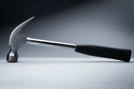 metal hammer on white table, work tool on black background