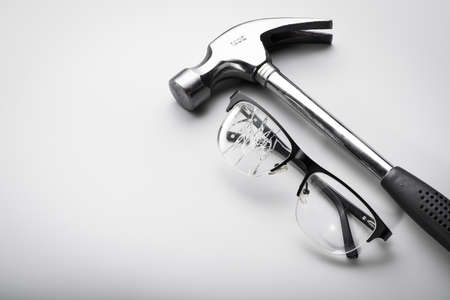 broken glasses with a metal mallet on white background. concept farewell with eyeglassesの写真素材