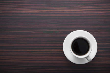 white coffee cup with black drink on wooden table, top viewの写真素材