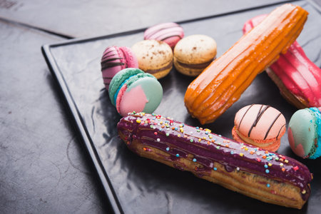 sweet dessert macaroon and eclairs on black board
