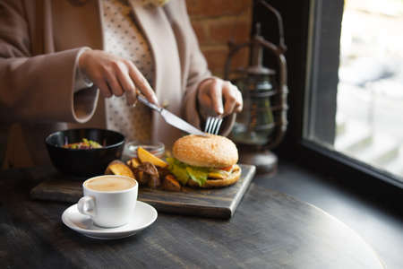 woman having lunch at a cafe, business lunch with coffee cup and burger, fast food の写真素材