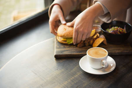 woman having lunch at a cafe, business lunch with coffee cup and burger, fast food の写真素材