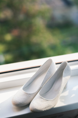 elegant white wedding shoes for women near the window.day of marriageの写真素材