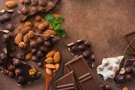 Tasty chocolate bars with nuts, fresh mint and almond on a stone background. Sweet foodの写真素材