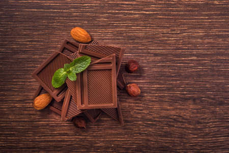 Pile of chocolate bars with nuts on a wooden tableの写真素材