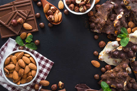 pieces of black and white chocolate with nuts, fresh mint and almond on black background, top viewの写真素材