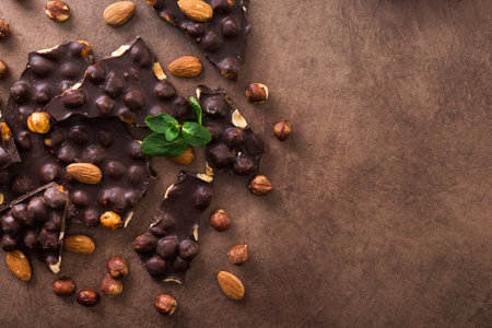 Tasty chocolate bars with nuts, fresh mint and almond on a stone background. Sweet foodの写真素材