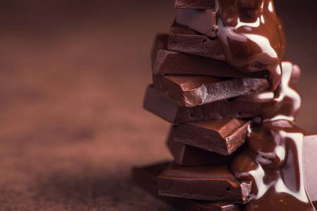 melted chocolate pouring into a piece of chocolate bars with green mint leaf on a tableの写真素材