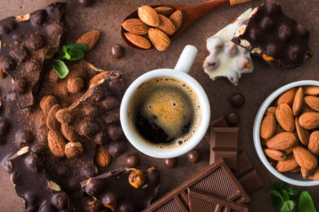 delicious sweet food chocolate with nuts and almond, coffee cup on stone background, top viewの写真素材