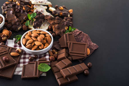 pieces of black and white chocolate with nuts, fresh mint and almond on black backgroundの写真素材