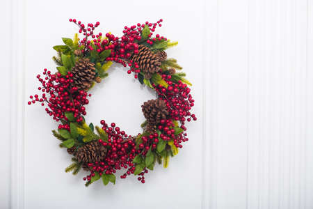 holiday christmas wreath with pine cones and red berry on a wallの写真素材
