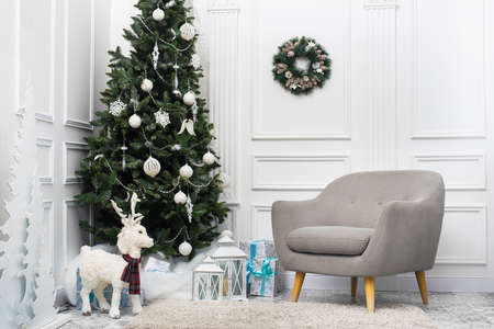White Christmas room with Christmas tree, decorative deer and armchair. Beautiful interiorの写真素材