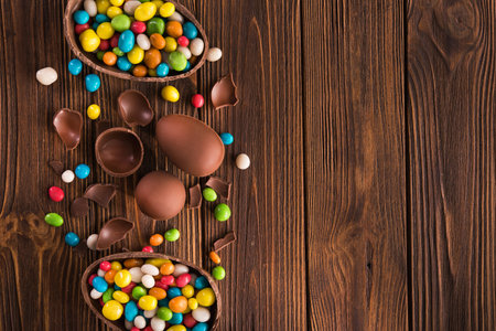 easter dessert tasty chocolate egg with color candy dragee on wooden tableの写真素材