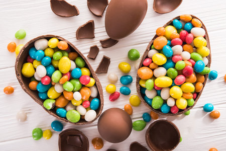 easter dessert tasty chocolate egg with color candy dragee on wooden table