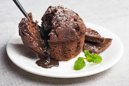 Sweet muffin cake with melted chocolate on a white plateの写真素材