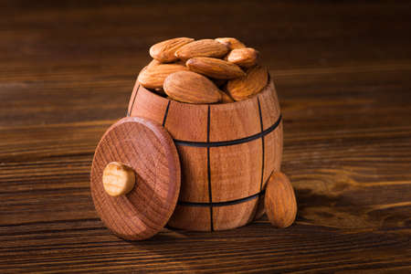 Raw almonds in a wooden barrel, on tableの写真素材