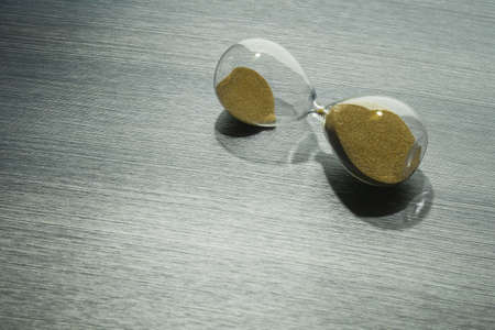 Time on the hourglass stopped. Clock on table. Pause in business, collapse.の写真素材