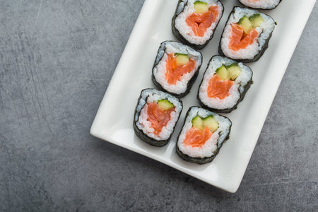 Sushi with salmon and cucumber, chopstick on a stone table. view from above