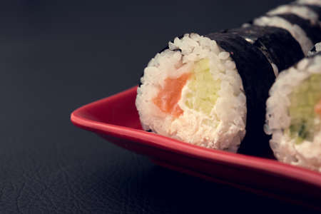 sushi roll with salmon and philadelphia on red plate. black background. Japanese foodの写真素材