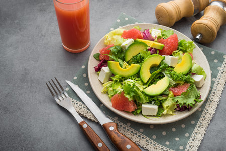 Fresh salad with avocado and grapefruit, glass of juice on a lunch. health eating conceptの写真素材