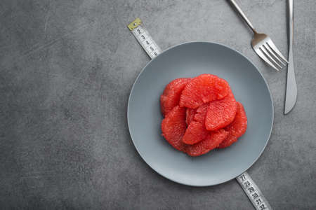 Fresh sliced grapefruit on a plate, stone table. Concept of diet. top viewの写真素材