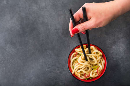 Japanese udon noodles with chopstick and red pepper on a background. spicy japanese mealの写真素材