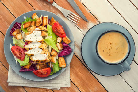 fresh chicken salad with blue coffee cup on a wooden table. appetizing lunch food background. top viewの写真素材