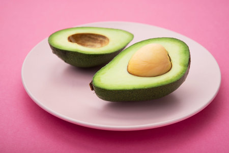 Fresh green avocado on a pink pastel background. healthy diet concept